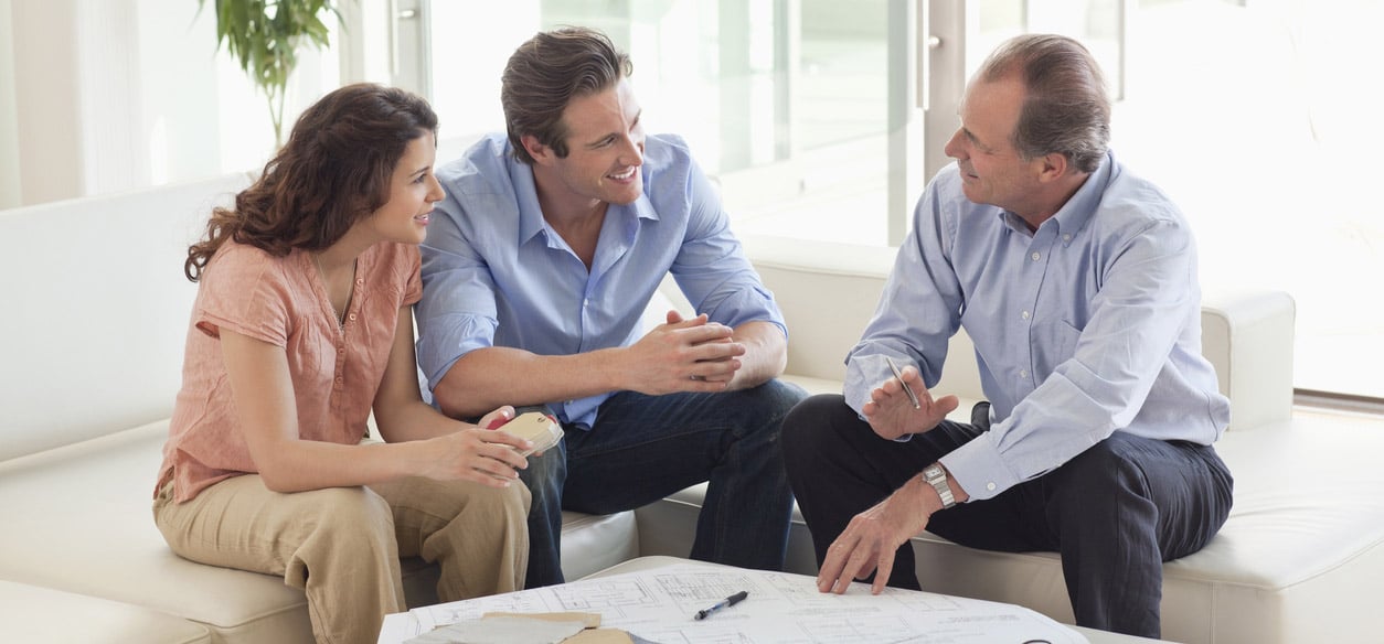 Couple Sitting On Sofa Talking To Financial Advisor