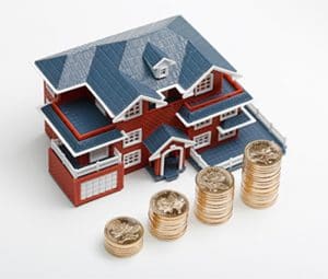 Rmb Coins Stacked In Front Of The Housing Model (house Prices, House Buying, Real Estate, Mortgage Concept)
